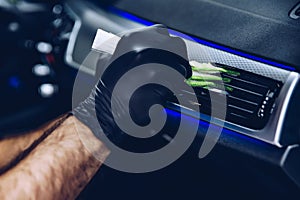 Man worker in car wash cleaning car air vent