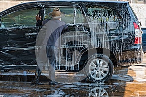 Man worker cleaning automobile with sponge on a car wash station