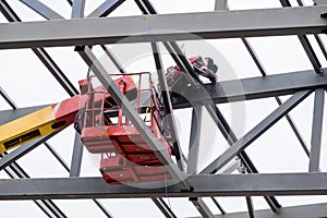 Man worker on a crane performs high-rise work on welding metal structures of new tower at height