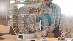 Man worker cutting a piece of wood with a circular saw in a workshop