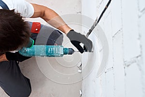 Man worker drilling wall with hammer drill, top view
