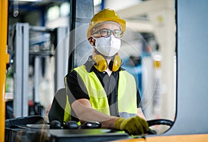 Man worker forklift driver with protective mask working in industrial factory or warehouse.