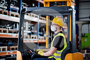 Man worker forklift driver with protective mask working in industrial factory or warehouse.