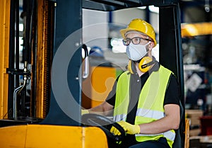 Man worker forklift driver with protective mask working in industrial factory or warehouse.