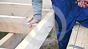 Man worker hammering while building wooden frame house.