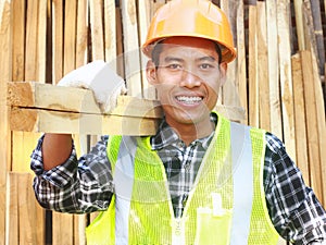 Man worker with helmet and safety vest carrying wood