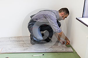 Man worker installing new wooden laminate flooring in new apparment photo