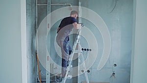 Man worker is making repairing in the apartment by putting putty on the walls. Construction house.