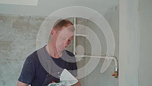 Man worker is making repairing in the apartment by putting putty on the walls. Construction house.