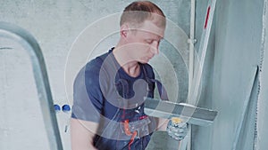 Man worker is making repairing in the apartment by putting putty on the walls. Construction house.