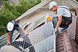 Man worker mounting solar panels on roof of house.