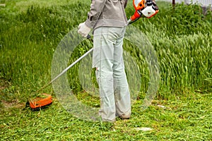 Man  worker mowing grass with trimmer