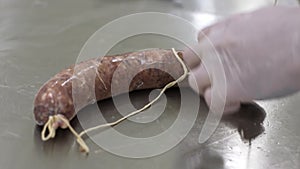Man worker packs fresh meat in shell and ties it with net. Meat factory.