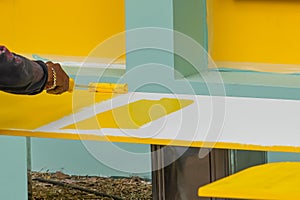 Man worker paints a surface with a roller with yellow paint