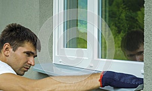 Man worker in protective gloves measuring external frame and PVC window metal sill size