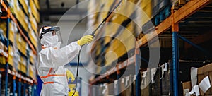 Man worker with protective mask and suit disinfecting industrial factory with spray gun.