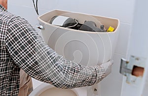 Man worker repairing with toilet tank in bathroom, closeup