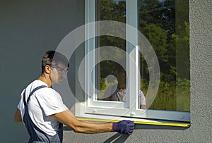 Man worker in safety glasses cleaning surface for PVC window metal sill installation