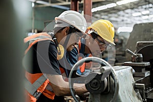 Man worker in safety helmet working on steel machine. Smart factory worker using machine in factory workshop