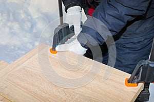 A man  a worker  secures the chipboard panels with two clamps