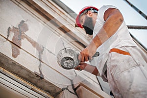 Man worker standing on scaffolding and restore old building facade