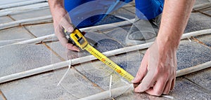 man worker takes measurements during the installation of a warm floor