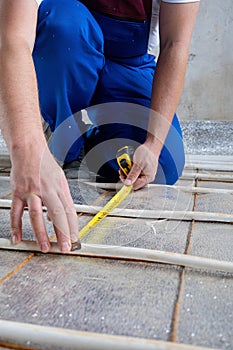 man worker takes measurements during the installation of a warm floor