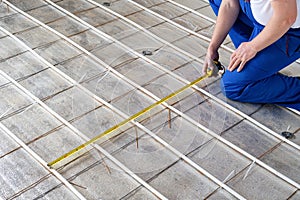 man worker takes measurements during the installation of a warm floor