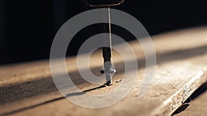 Man the worker tightens the screw with a screwdriver. Screws screwdriver twist in wooden board. Joinery and construction