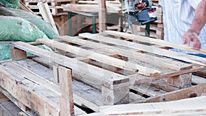 Man Worker in a timber factory using a nail gun to make a wooden pallet