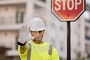 Man in worker uniform and hardhat with open hand doing stop sign with serious and confident expression, defense gesture