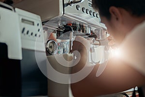 Man worker in uniform inspecting coffee machine in own workshop