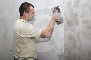 Man worker using float to apply first layer of putty