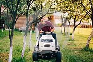 Man worker using lawnmower and cutting garden grass. Backyard maintanance works
