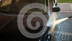 Man, worker, washes the car. Car wash using high pressure water jet