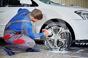 Man worker washing car`s alloy rims on a car wash