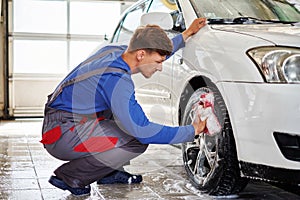 Man worker washing car`s alloy rims on a car wash