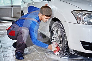 Man worker washing car`s alloy rims on a car wash