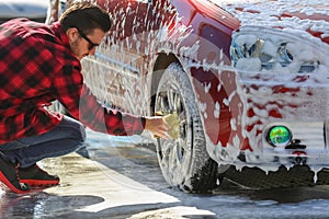 Man worker washing car`s alloy wheels on a car wash