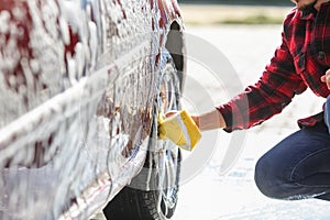 Man worker washing car`s alloy wheels on a car wash