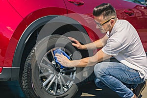 Man worker washing car`s alloy wheels on a car wash. Car wash with soap.