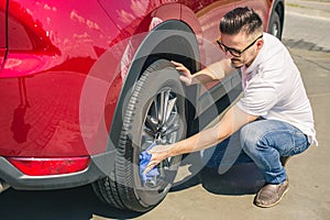 Man worker washing car`s alloy wheels on a car wash. Car wash with soap.