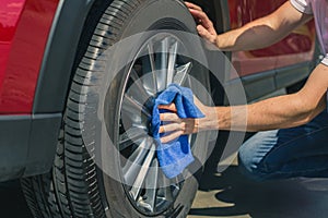 Man worker washing car`s alloy wheels on a car wash. Car wash with soap.