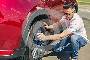 Man worker washing car`s alloy wheels on a car wash. Car wash with soap.