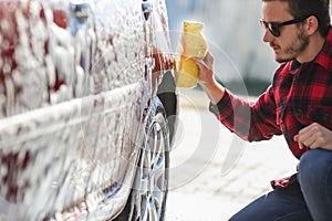 Man worker washing car`s alloy wheels on a car wash