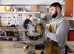 Man worker during work in workshop, woman on background