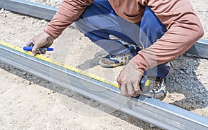 Man workers' hands use measuring tape to measure the length of the steel part in homebuilding.