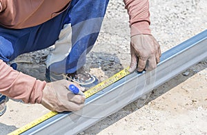 Man workers' hands use measuring tape to measure the length of the steel part in homebuilding.