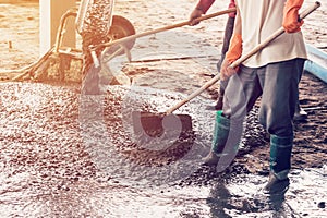 Man workers spreading freshly poured concrete mix on building