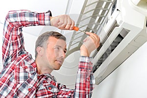 Man working on air conditioning unit, flap open